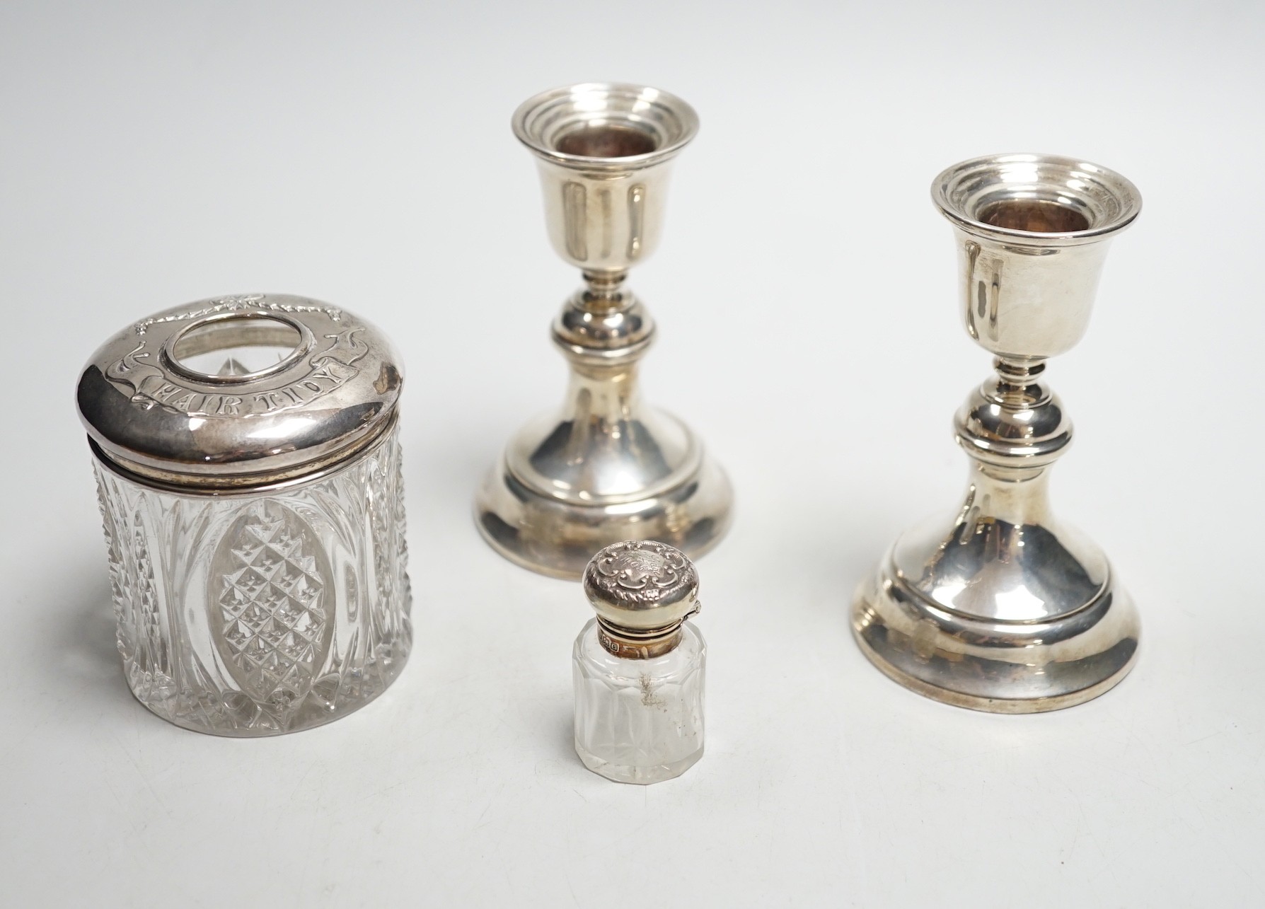 A pair of 1930's silver mounted dwarf candlesticks, 10cm, a silver mounted glass hair tidy and a scent bottle.
